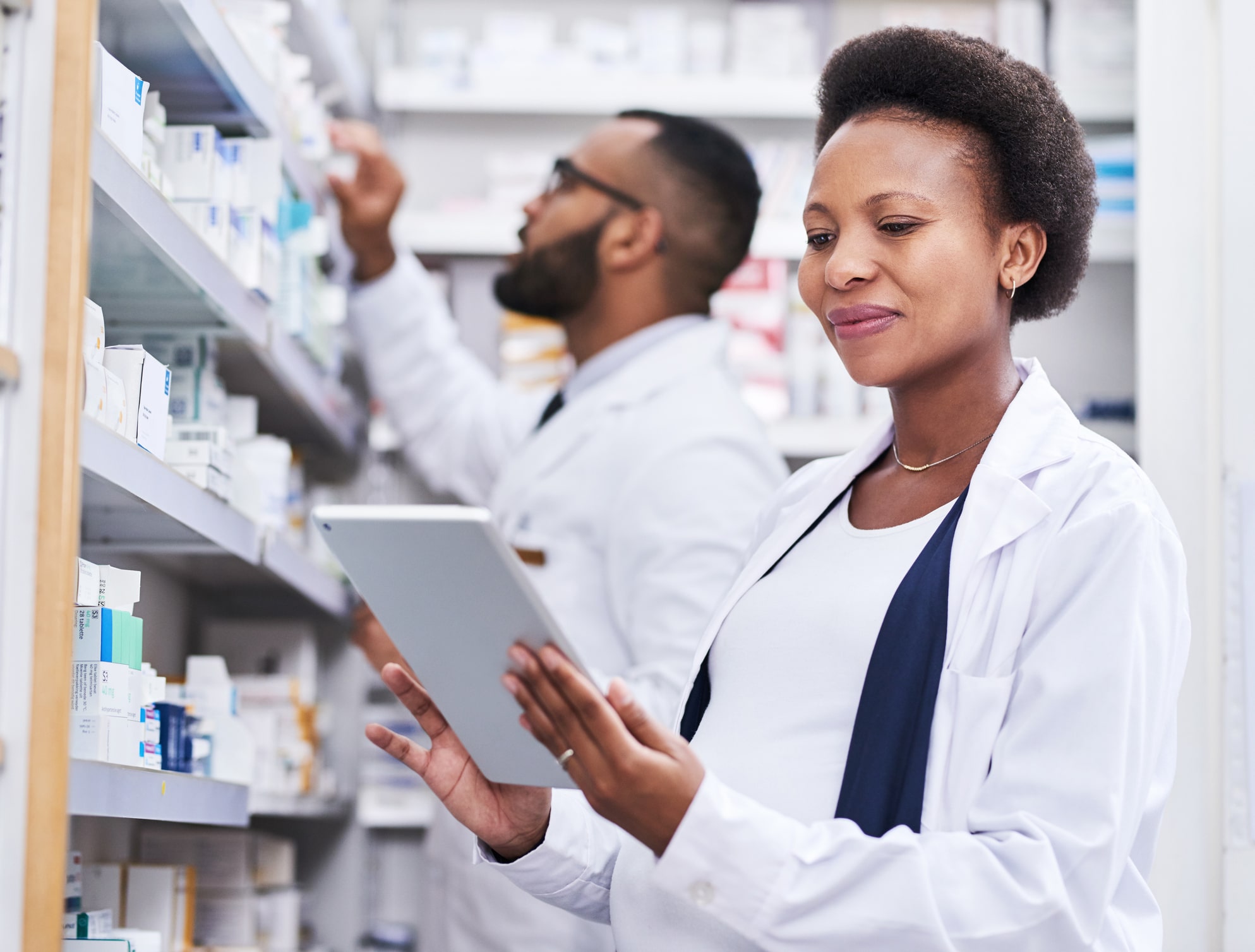 Shot of a pharmacist using a digital tablet while working with her male colleague in a pharmacy