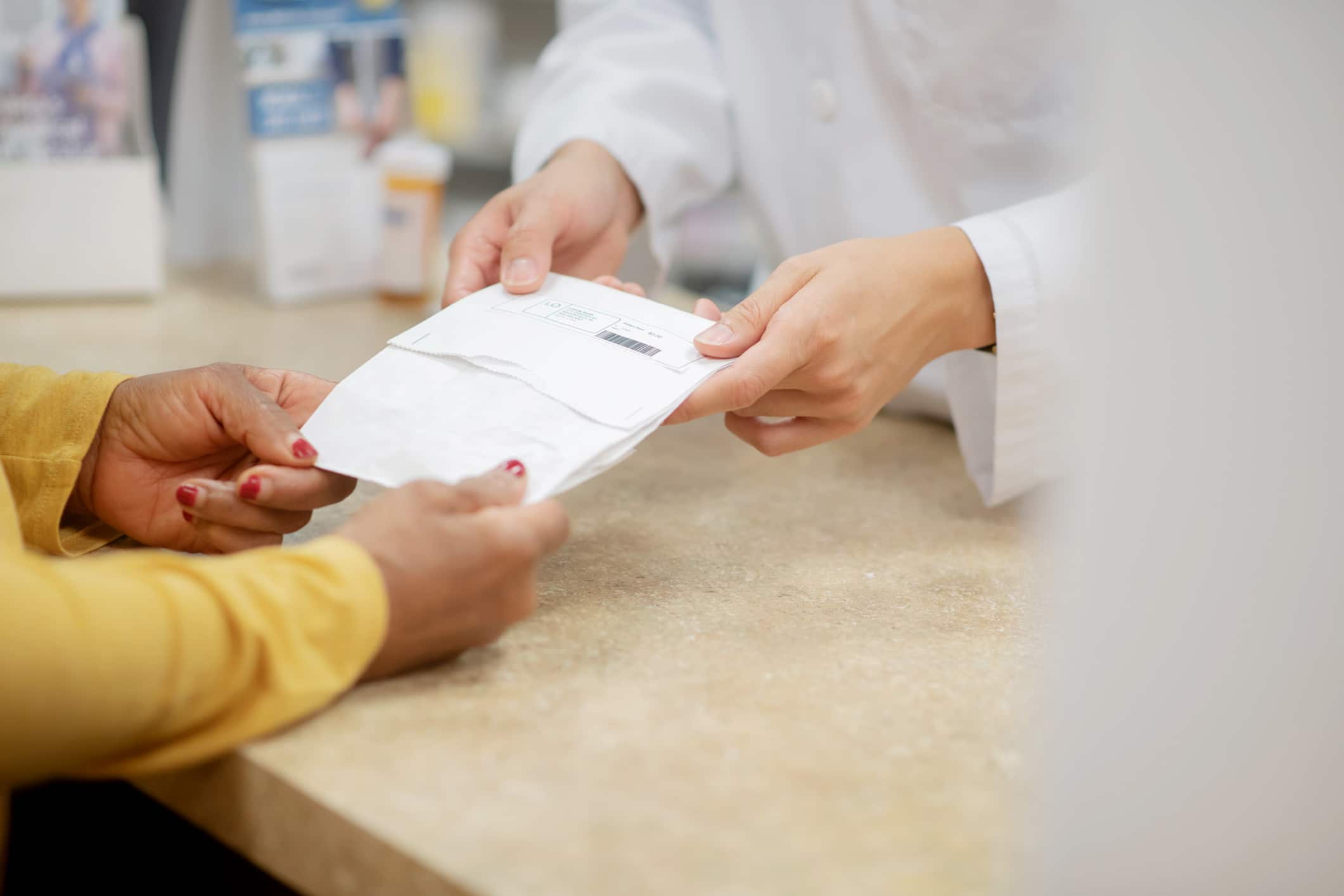 A pharmacist hands over a patients prescription medication after explaining the side effects and instructions for taking it