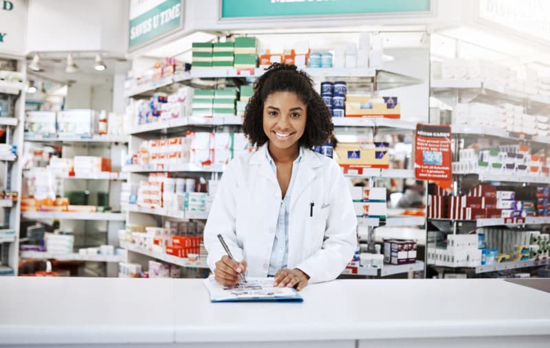 Young pharmacy student on internship, standing at the counter in a pharmacy