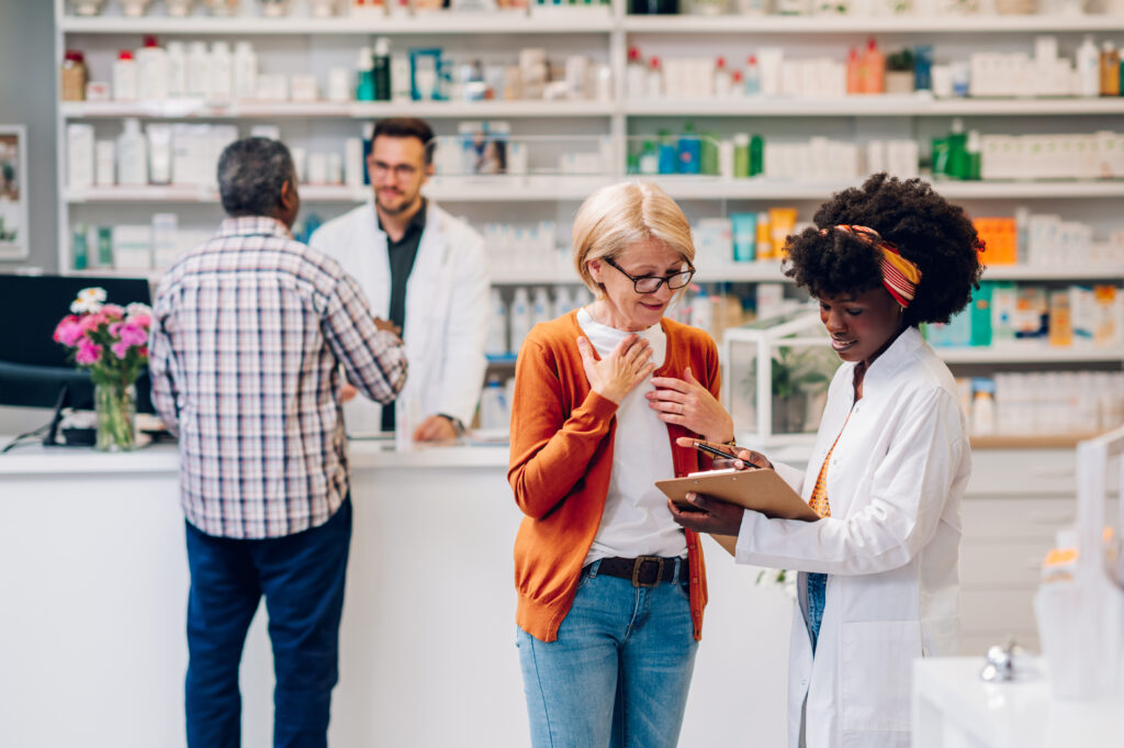 Two pharmacists in a pharmacy consulting with patients.